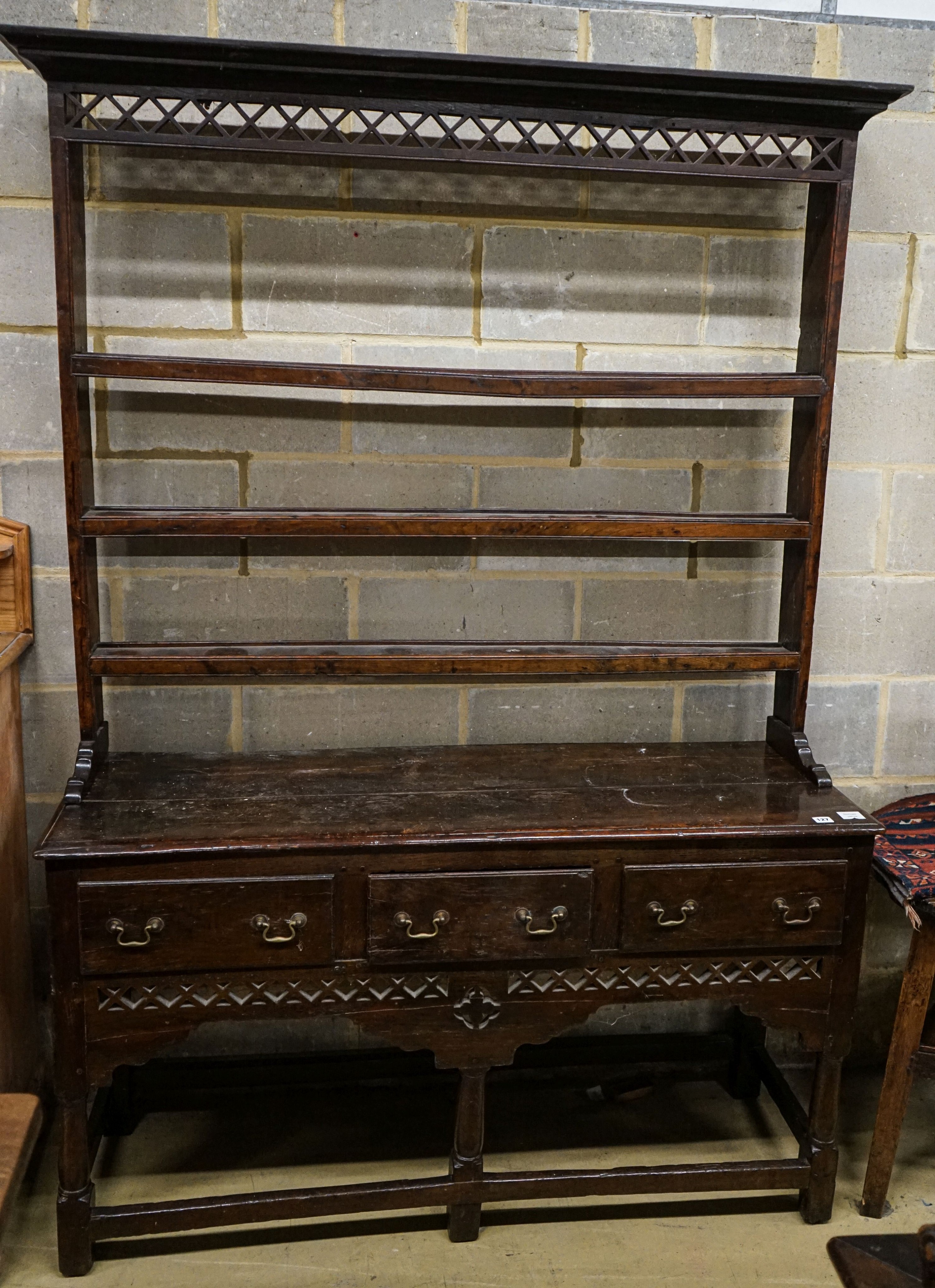 A mid 18th century oak dresser, with pierced cornice and three shelf rack over three drawers, with pierced frieze and turned and squared underframe, width 142cm, depth 46cm, height 204cm